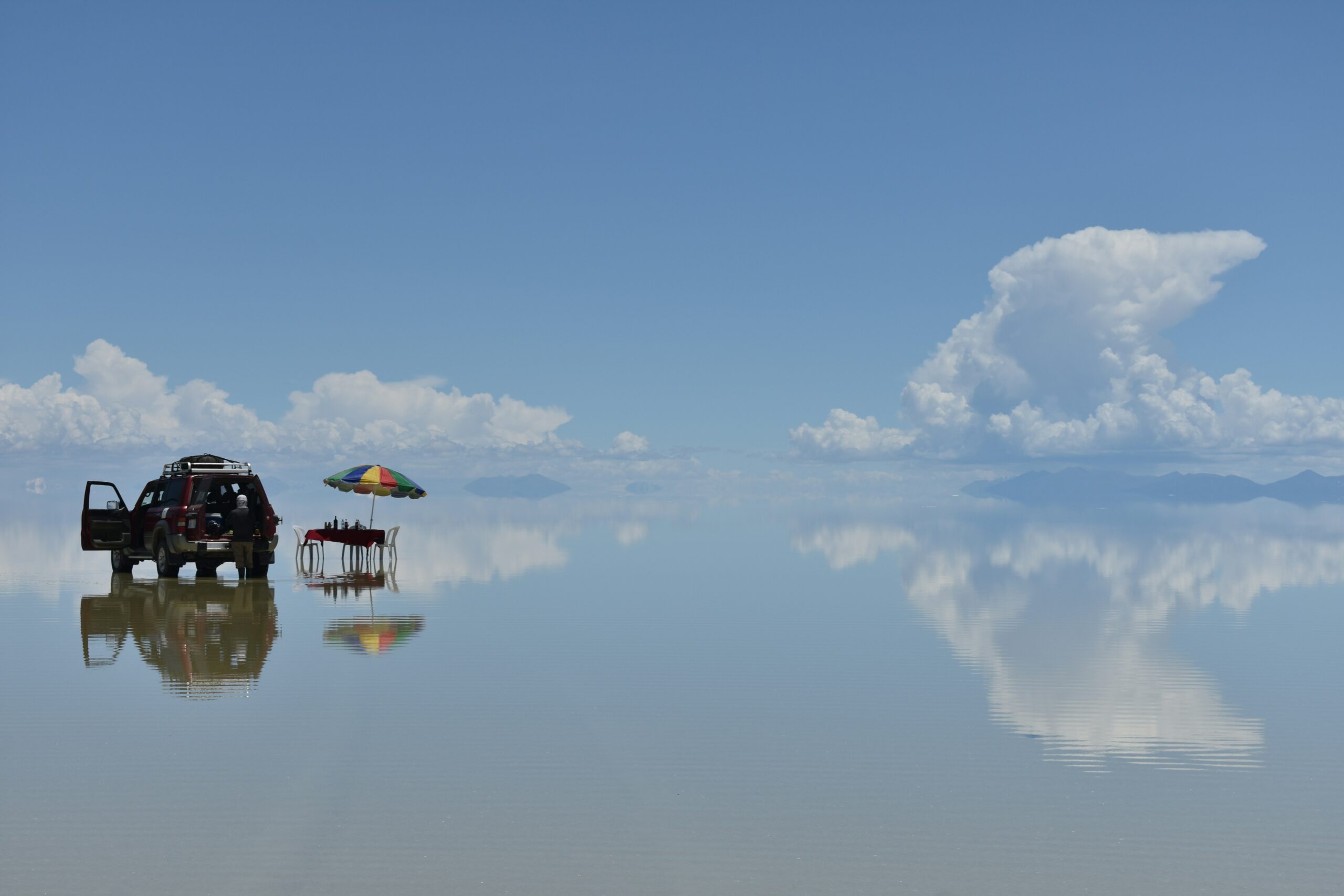 Fuoristrada riflesso sul Salar de Uyuni coperto d'acqua, Bolivia