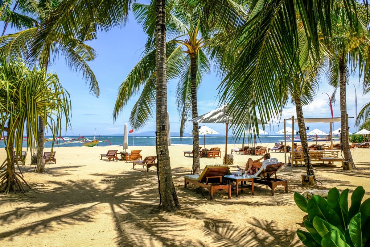 Palme e lettini sulla spiaggia di Sanur, mare del viaggio a Bali