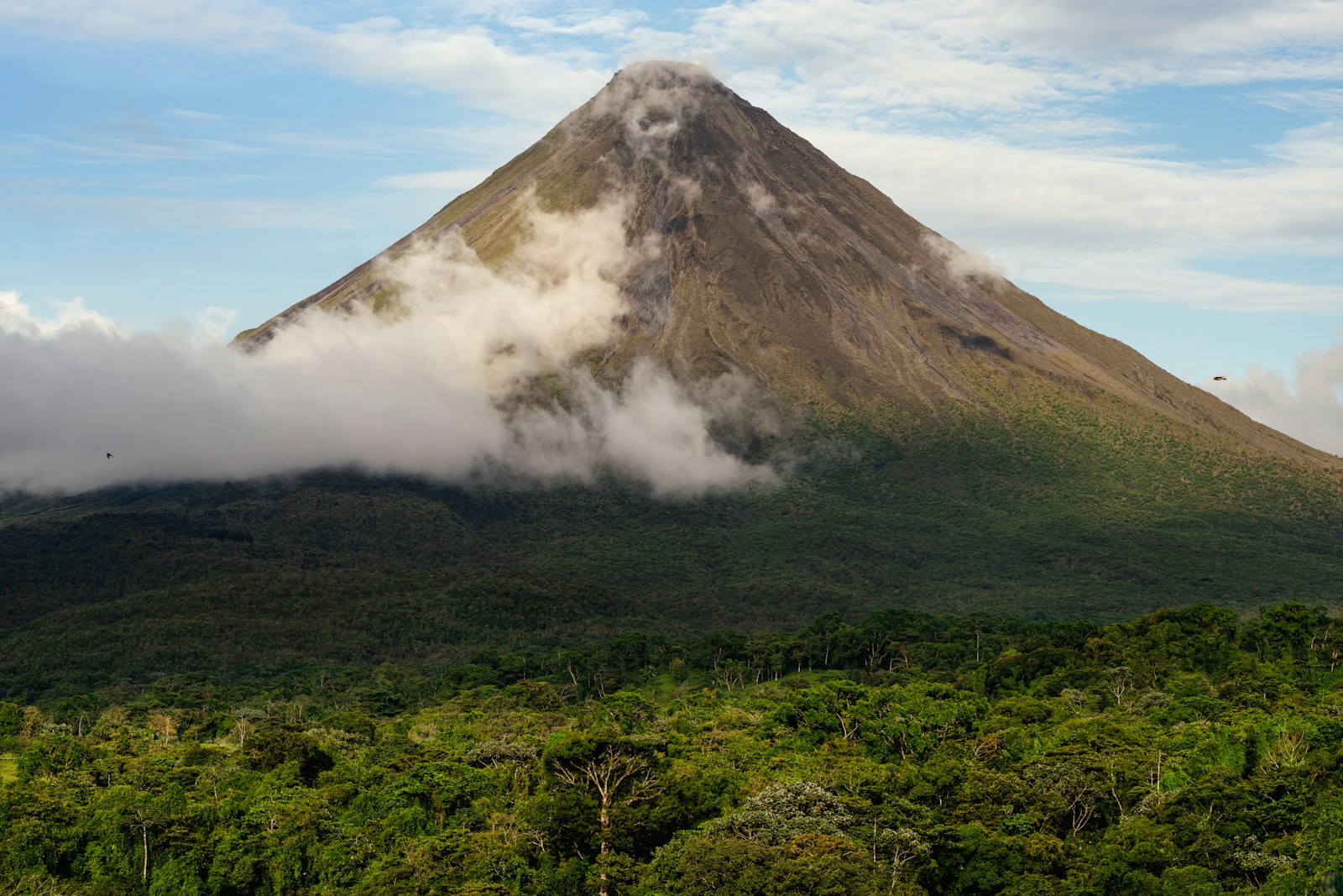 Il vulcano Arenal avvolto dalle nuvole sopra la foresta, viaggio in Costa Rica